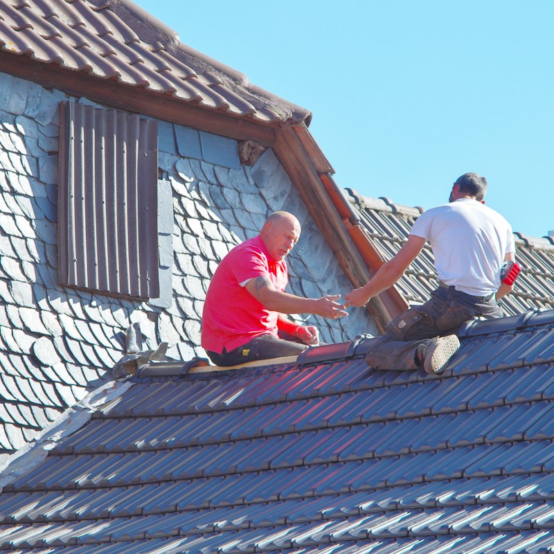 Deux ouvriers au travail sur la toiture en ardoise d'une maison