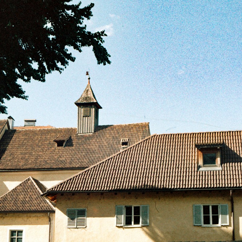 Toitures en tuiles de vieux bâtiments avec petites fenêtres de toit et lucarnes, sous un ciel bleu