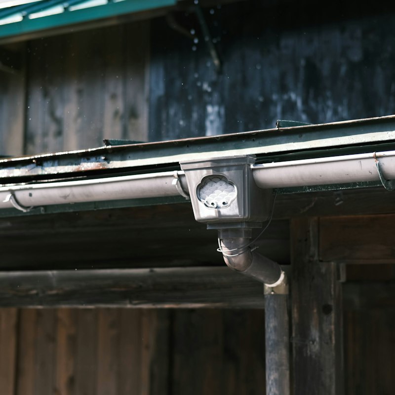 Gouttière métallique et départ de descente d'eau pluviale sur une façade en bois